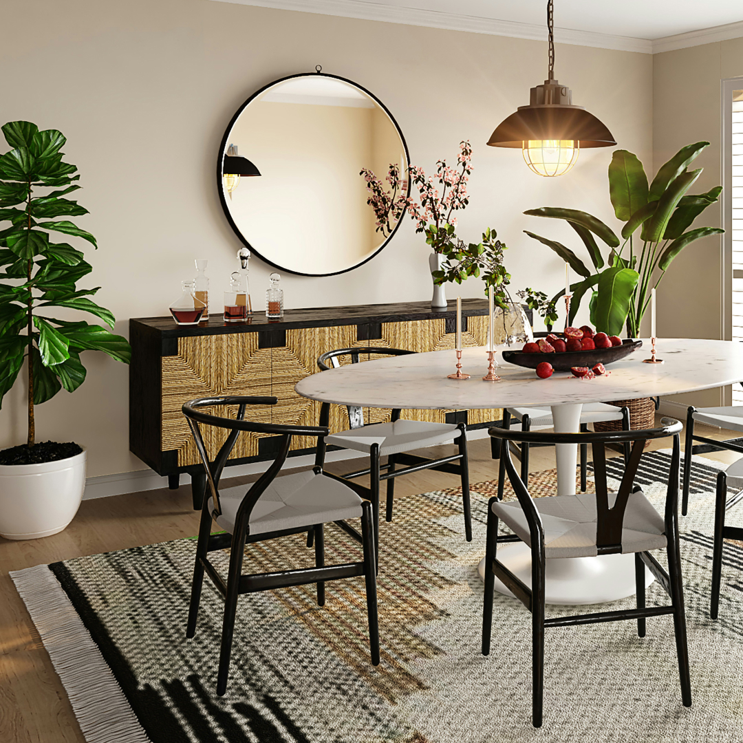 A stylish dining room featuring a marble oval table with modern black chairs, a large round mirror on the wall, a buffet cabinet with textured doors, and indoor plants, under a pendant light.