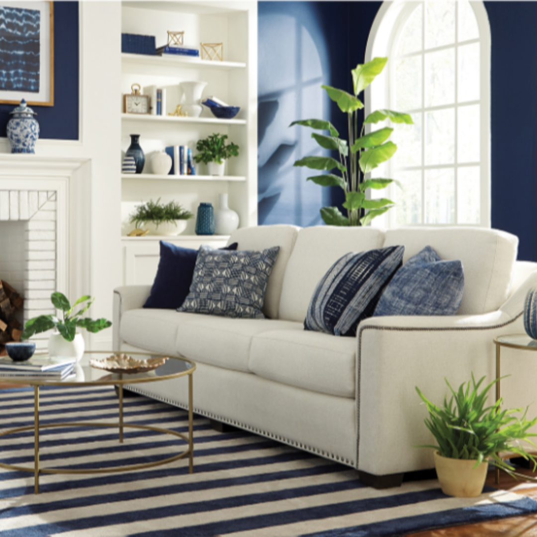 A living room with striped rug, blue accent walls and a white couch.