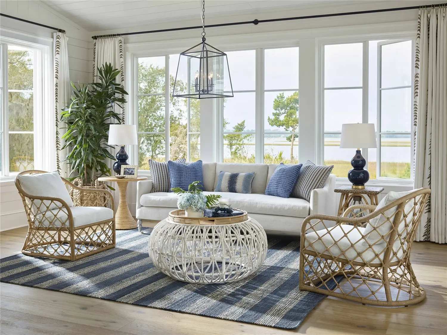 Coastal living room with wicker furniture, blue accents, and water view.