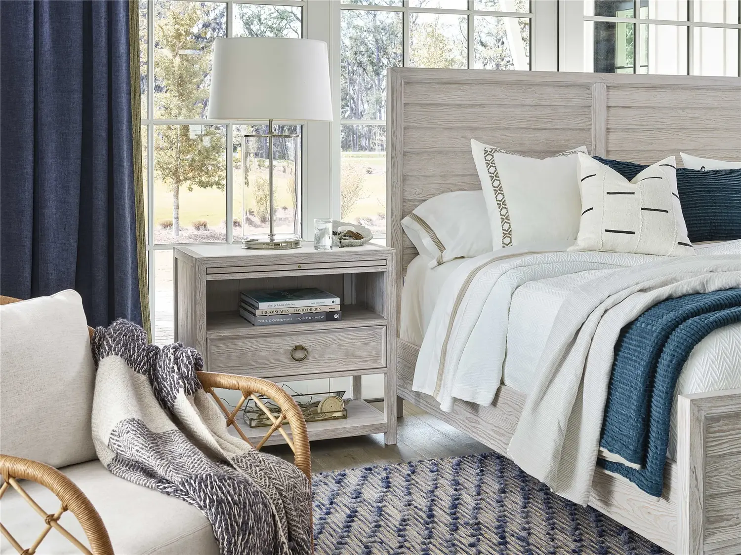 Modern bedroom with light wood furniture, blue accents, and a cozy chair.