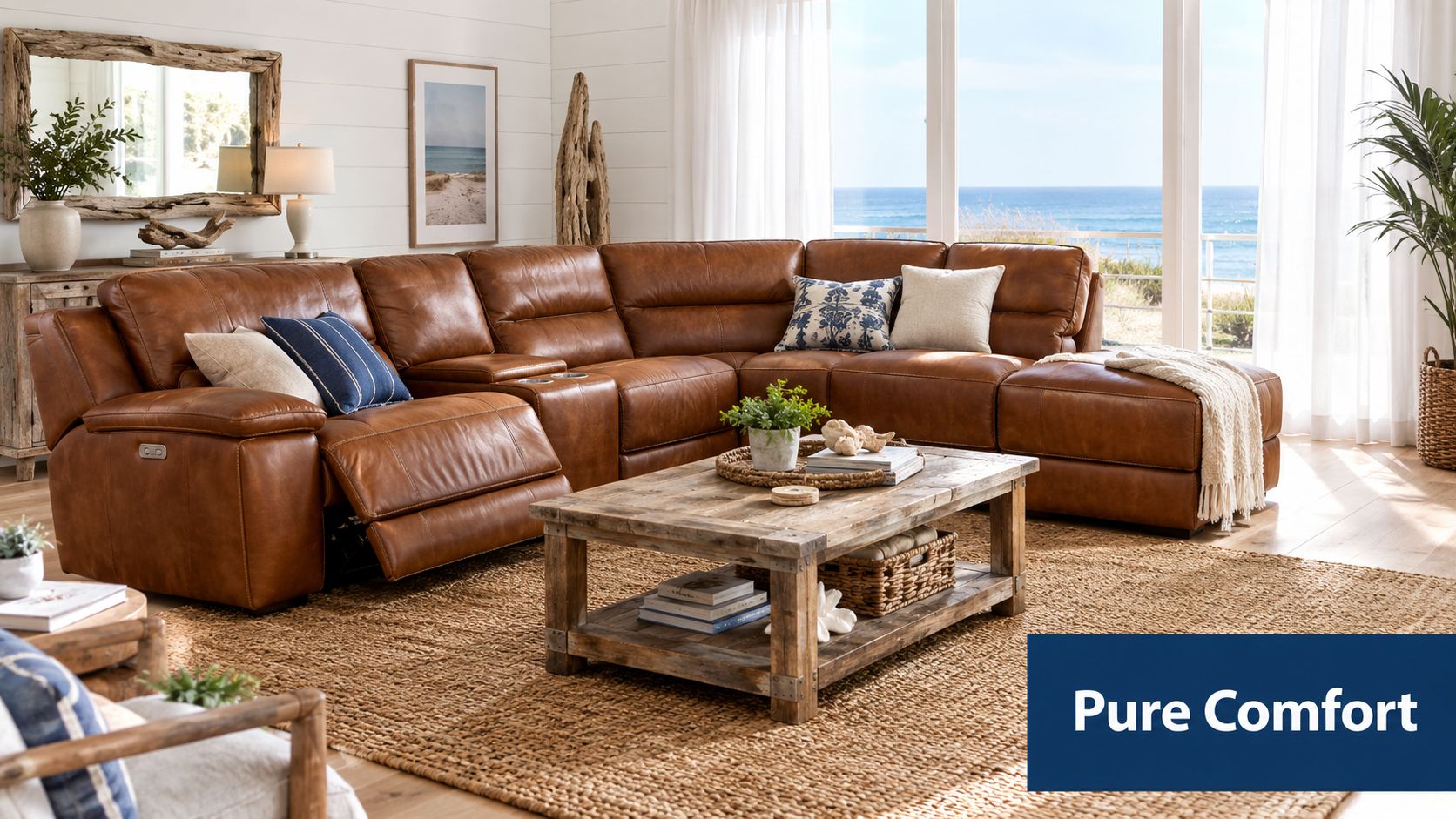 A luxurious brown leather reclining sectional sofa in a bright coastal-style living room with a coffee table.