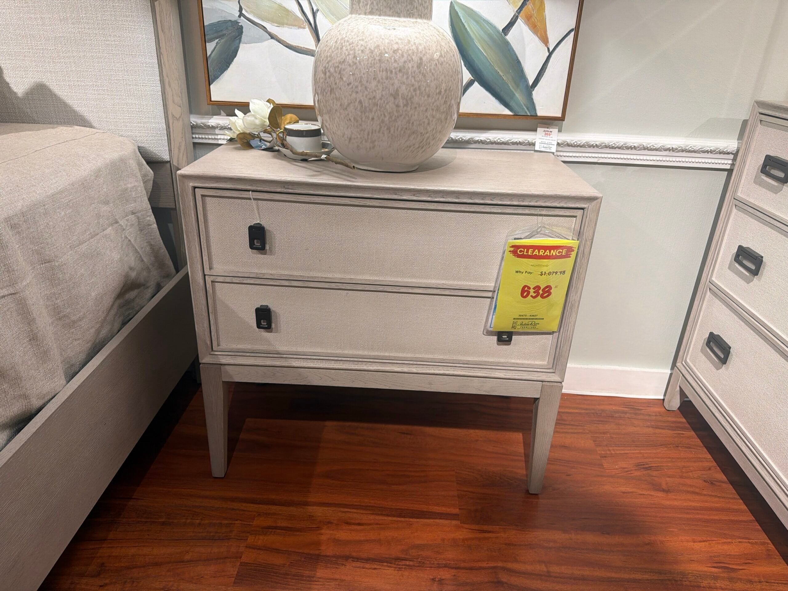 0e10d606-41c7-4233-99b8-f90dfa2aad10-36958-000011c49406516d_file Two-drawer light-toned nightstand with textured drawer fronts and black hardware.